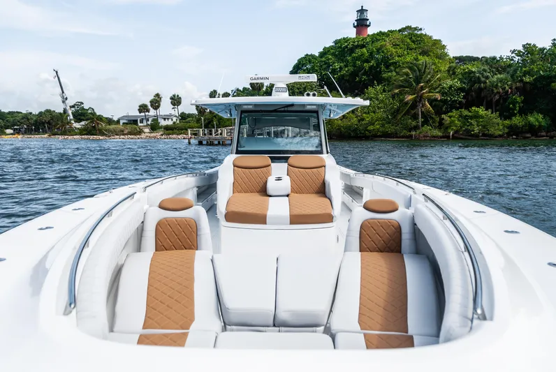 Relentless Yacht Photos Pics Luxury HCB 53 Sueños boat with tan seating, cruising near a lighthouse, 2021 model.