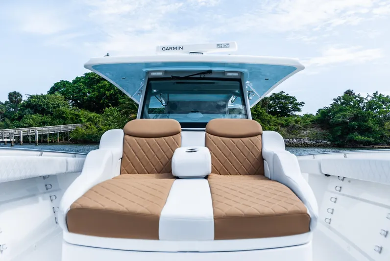 Relentless Yacht Photos Pics 2021 HCB 53 Sueños boat with luxurious tan seating, docked near lush greenery.