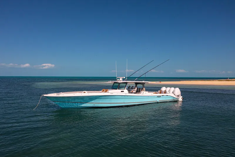 Relentless Yacht Photos Pics HCB 53 Sueños 2021 boat anchored near sandy beach under clear blue sky.