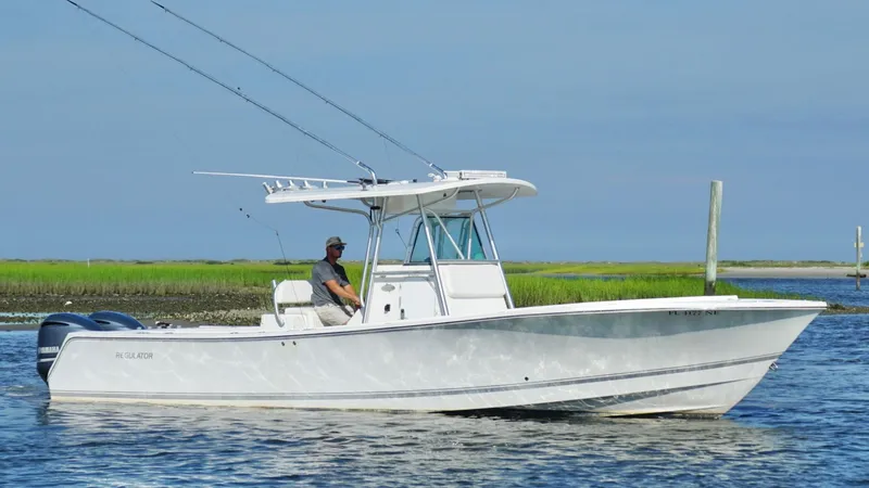  Yacht Photos Pics 2006 Regulator 32 FS boat on water with person, clear sky, and grassy shoreline.