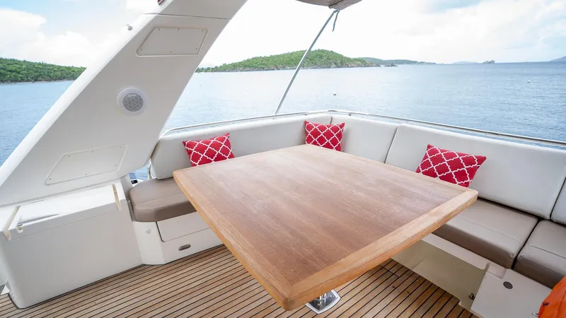  Yacht Photos Pics Luxurious 2013 Prestige 620 yacht deck with wooden table and cushioned seating, overlooking serene waters.