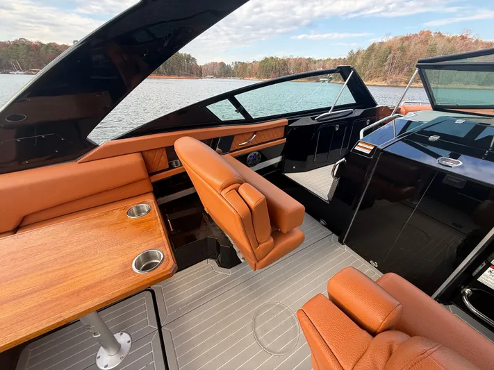  Yacht Photos Pics 2022 Cruisers Yachts 338 CX SB interior with brown leather seating and wooden table on a lake.