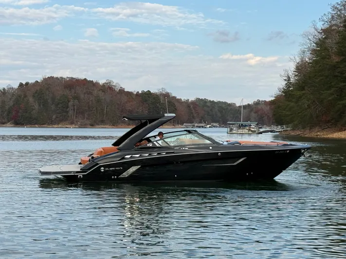  Yacht Photos Pics 2022 Cruisers Yachts 338 CX SB on a serene lake with wooded shoreline.