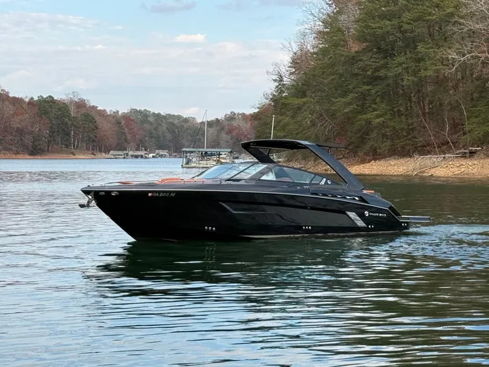  Yacht Photos Pics 2022 Cruisers Yachts 338 CX SB on a serene lake, surrounded by trees.