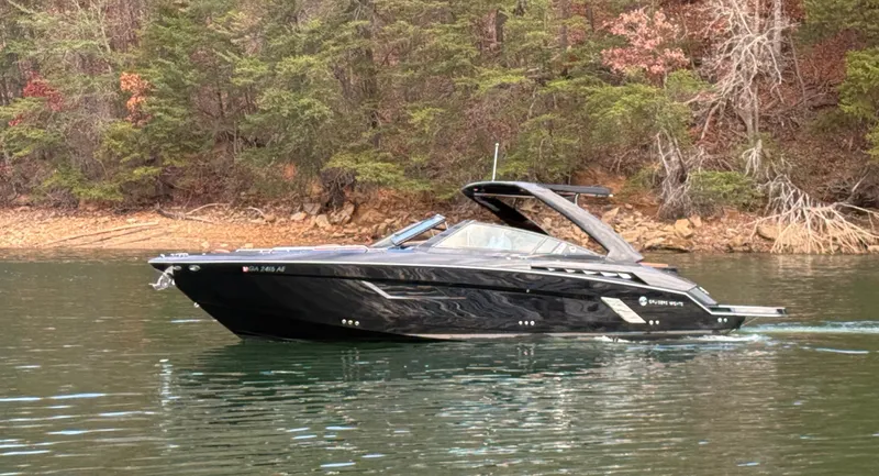  Yacht Photos Pics 2022 Cruisers Yachts 338 CX SB boat cruising on a serene lake with forested shoreline.