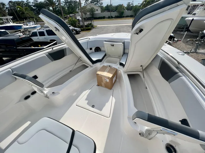  Yacht Photos Pics 2025 Robalo R300 boat interior with open storage compartments and a package on deck.