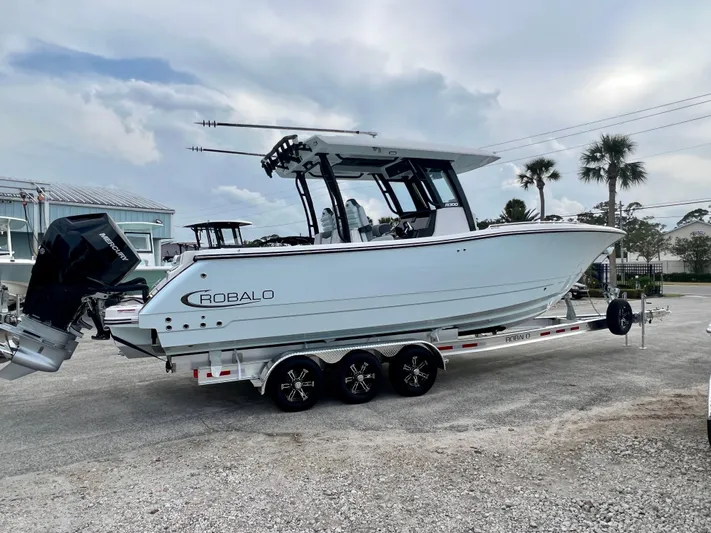  Yacht Photos Pics 2025 Robalo R300 boat on trailer, parked outdoors under cloudy sky.