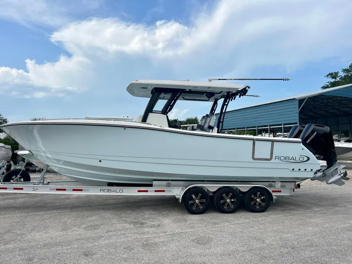  Yacht Photos Pics 2025 Robalo R300 boat on trailer, side view, under a partly cloudy sky.