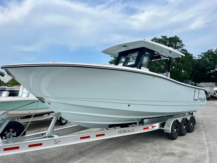  Yacht Photos Pics 2025 Robalo R300 boat on trailer, sleek design, parked outdoors under cloudy sky.