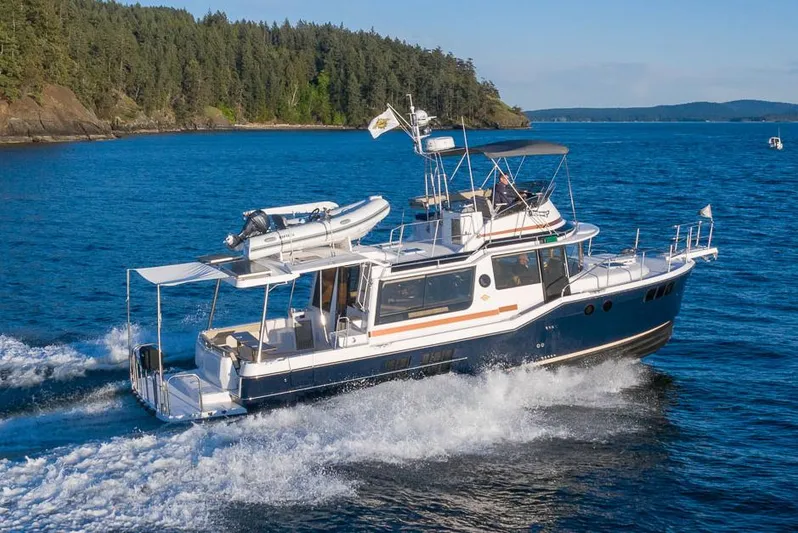  Yacht Photos Pics Manufacturer Provided Image: 2025 Ranger Tugs R-43 CB cruising on blue water near forested shoreline.