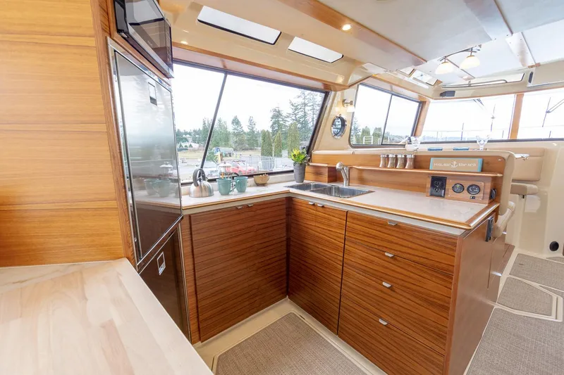  Yacht Photos Pics Manufacturer Provided Image: Luxurious 2025 Ranger Tugs R-43 CB yacht kitchen with modern wood cabinetry and large windows.