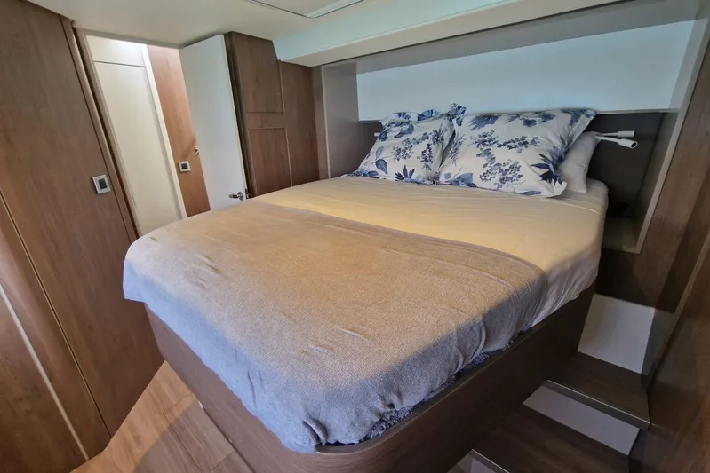 Only One Life Yacht Photos Pics Cozy bedroom in 2022 Bali 5.4 Open Space yacht with wooden interior and floral pillows.