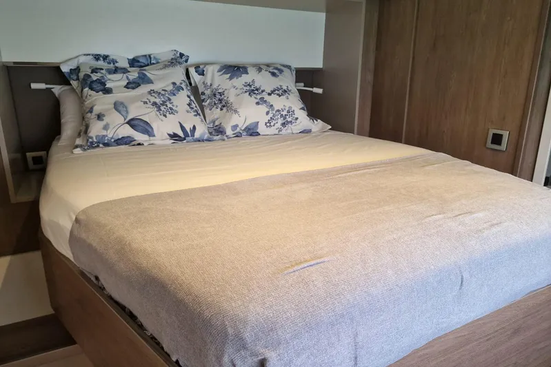 Only One Life Yacht Photos Pics Cozy bed with floral pillows in a 2022 Bali 5.4 Open Space yacht cabin.