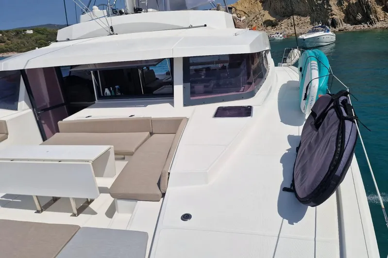 Only One Life Yacht Photos Pics 2022 Bali 5.4 Open Space yacht with spacious deck and seating area, anchored near rocky coastline.