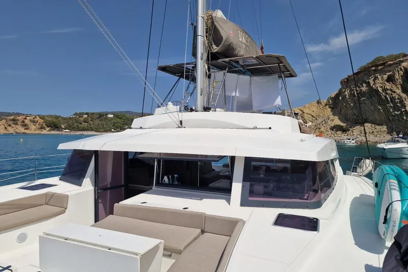 Only One Life Yacht Photos Pics 2022 Bali 5.4 Open Space catamaran anchored near rocky coastline, featuring spacious deck.