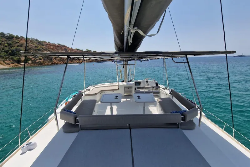 Only One Life Yacht Photos Pics 2022 Bali 5.4 Open Space yacht on serene blue waters near a rocky coastline.