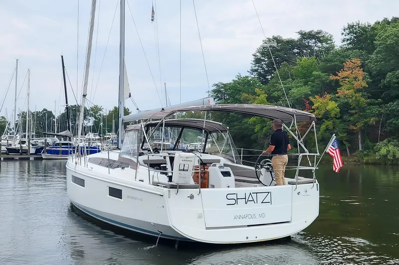 Shatzi Yacht Photos Pics 2022 Jeanneau Sun Odyssey 410 sailboat navigating a marina, with trees in the background.