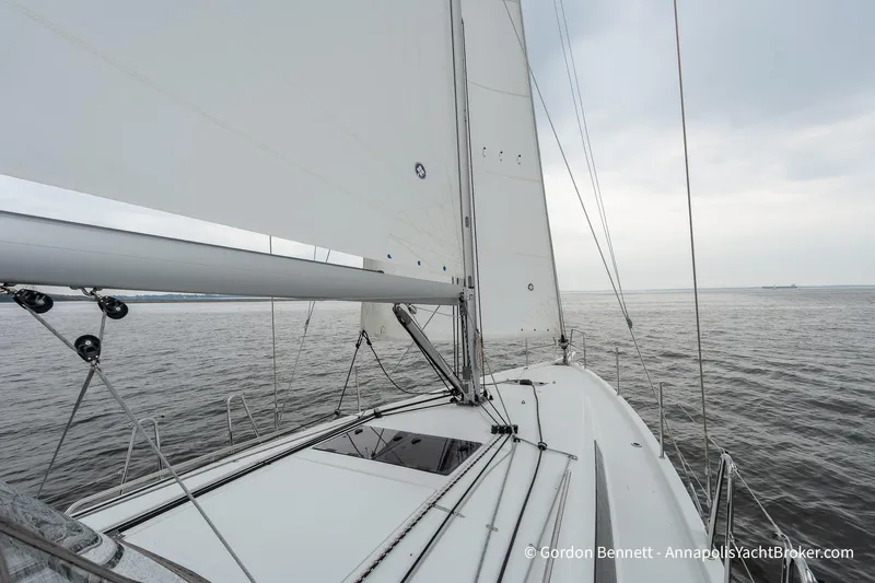 Shatzi Yacht Photos Pics 2022 Jeanneau Sun Odyssey 410 sailing on calm waters under a cloudy sky.