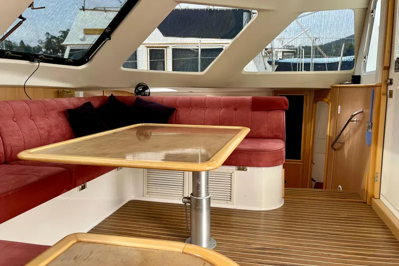  Yacht Photos Pics Interior of 2008 Seawind 1160 catamaran with red seating and wooden table.
