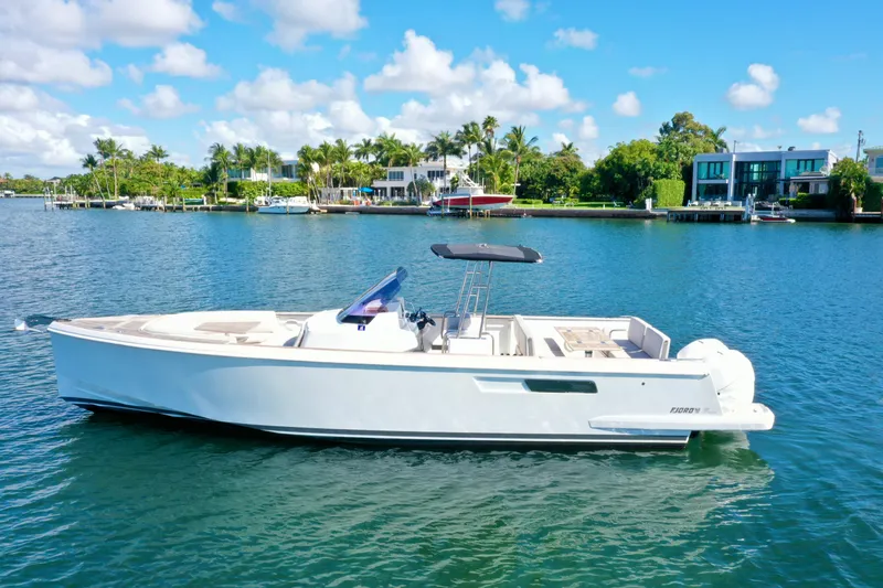  Yacht Photos Pics 2019 Fjord 36' Open boat on a sunny waterfront with palm trees and luxury homes.