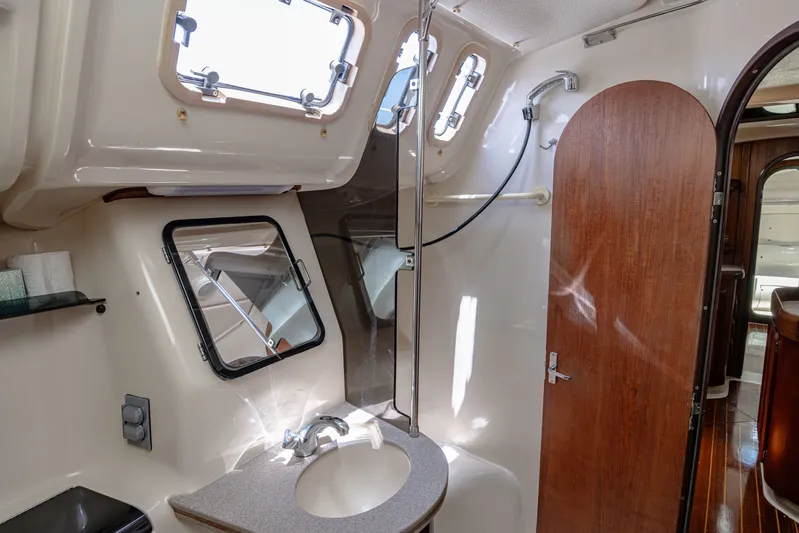 Into The Mystic Yacht Photos Pics Interior of 1996 Hunter 430 yacht bathroom with sink, mirror, and wooden door.