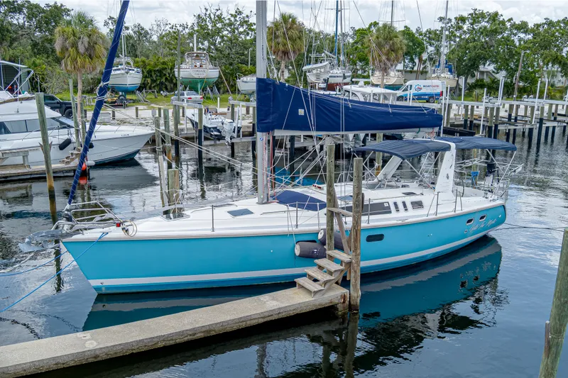 Into The Mystic Yacht Photos Pics Sailboat docked in marina, 1996 Hunter 430 model, vibrant blue hull, calm water reflections.