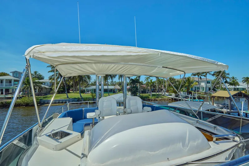  Yacht Photos Pics 2003 McKinna 58 Pilothouse yacht with canopy, docked near waterfront homes.