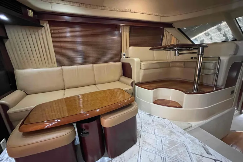 Beira Mar Yacht Photos Pics Luxurious interior of 2005 Sea Ray 420 Sedan Bridge yacht with leather seating and wooden table.