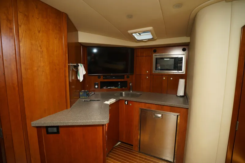 Hi Ho Silver Yacht Photos Pics 2011 Rampage 41 Express yacht interior with kitchenette, TV, and wooden cabinetry.
