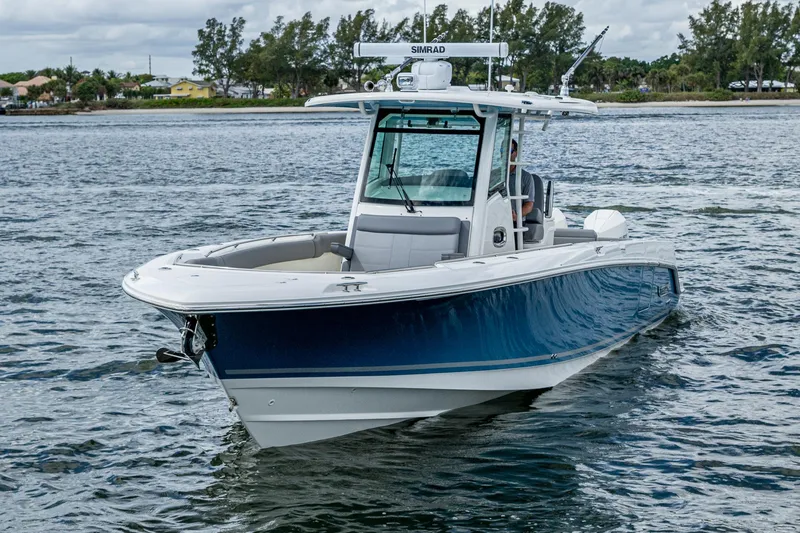  Yacht Photos Pics 2023 Boston Whaler 330 Outrage boat cruising on a calm waterway.
