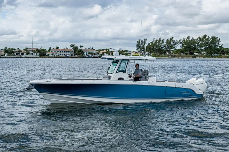  Yacht Photos Pics 2023 Boston Whaler 330 Outrage boat cruising on a calm waterway.