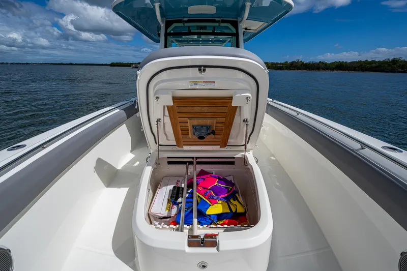  Yacht Photos Pics 2023 Boston Whaler 330 Outrage boat with open storage compartment, colorful gear inside.