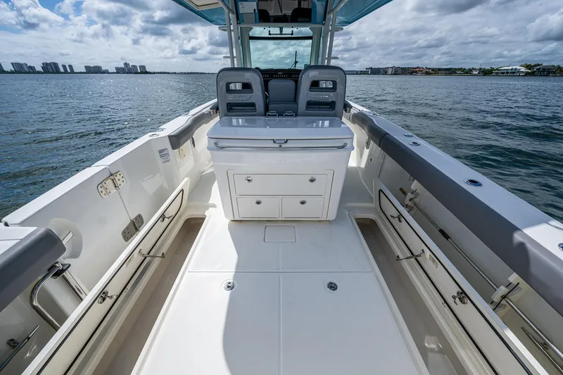  Yacht Photos Pics 2023 Boston Whaler 330 Outrage boat interior with seating and storage, on calm water.
