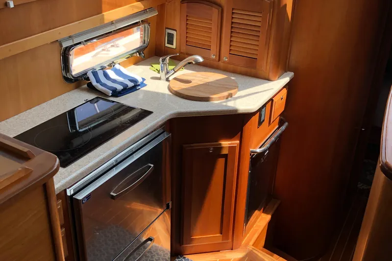 Yacht Photos Pics 2009 Sabre 40 Sedan yacht kitchen with stove, sink, and wooden cabinetry.