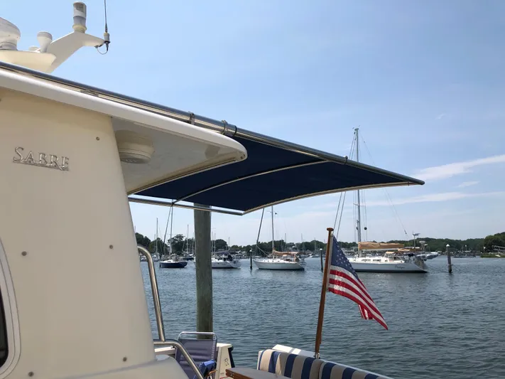  Yacht Photos Pics 2009 Sabre 40 Sedan yacht docked with American flag, overlooking marina with sailboats.