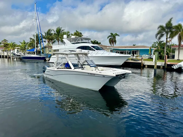  Yacht Photos Pics 2021 World Cat 280 DC-X boat cruising in a marina with palm trees and yachts.