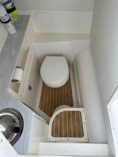 Yacht Photos Pics 2021 World Cat 280 DC-X boat bathroom with toilet, sink, and wooden flooring.
