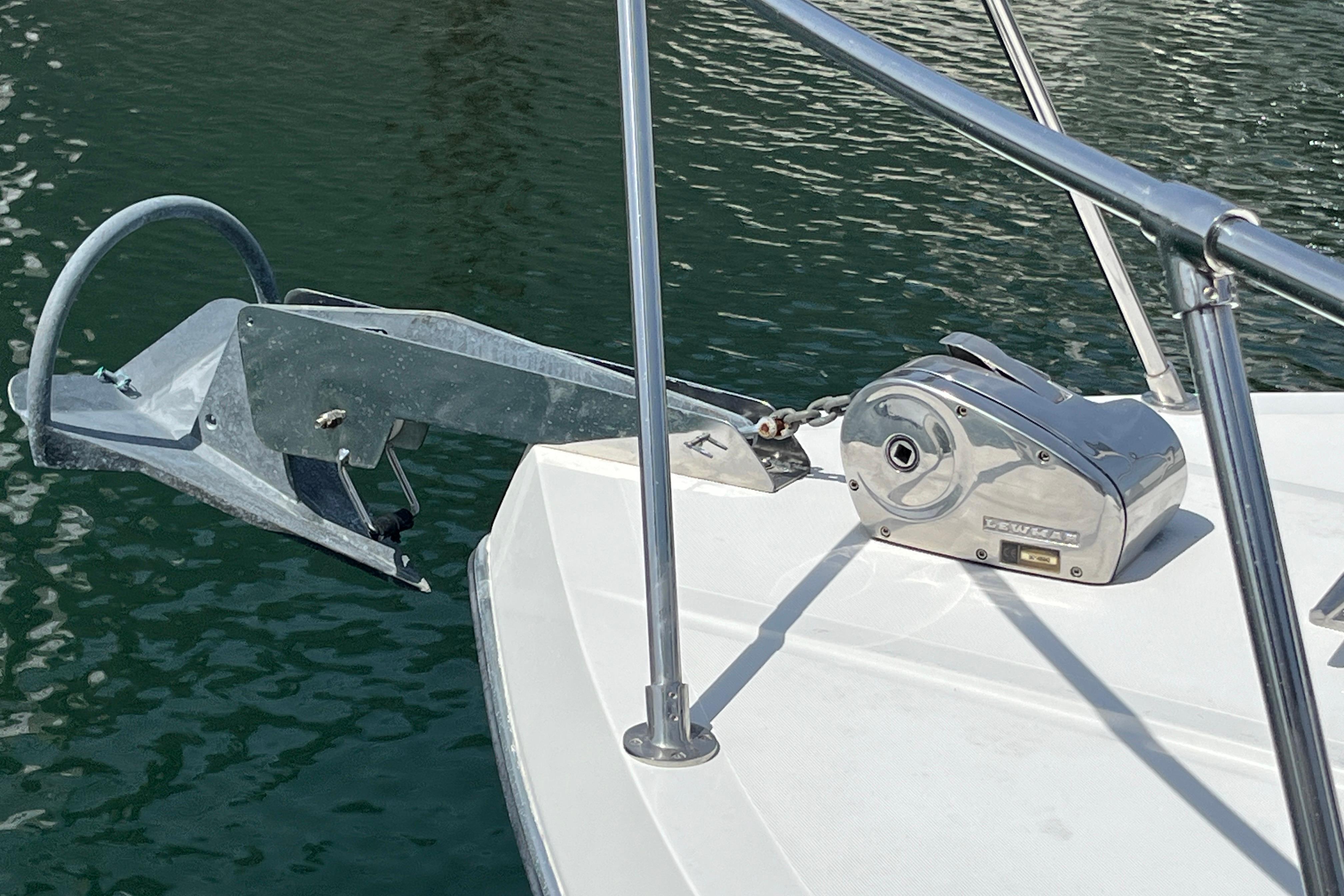Anchor and winch on 2006 Commander 26 Sedan boat, docked on calm water.