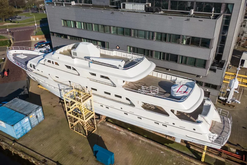 Valeria Yacht Photos Pics Aerial view of a 1975 Feadship motoryacht docked near a modern building.