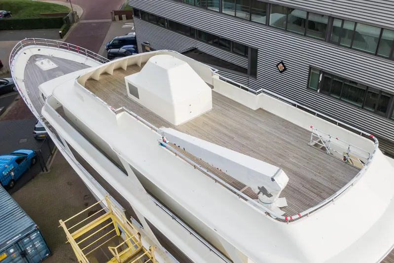 Valeria Yacht Photos Pics 1975 Feadship Motoryacht with spacious deck, docked near modern building.