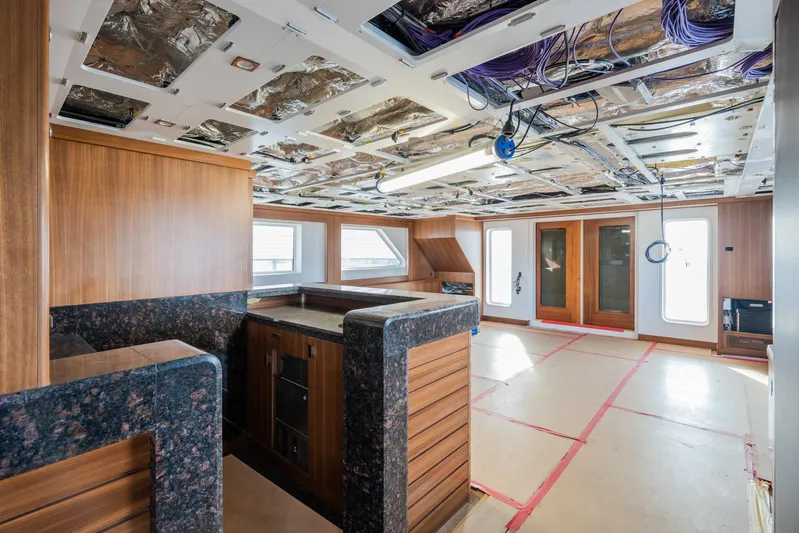 Valeria Yacht Photos Pics Interior of a 1975 Feadship motoryacht under renovation, featuring wood paneling and exposed ceiling wiring.