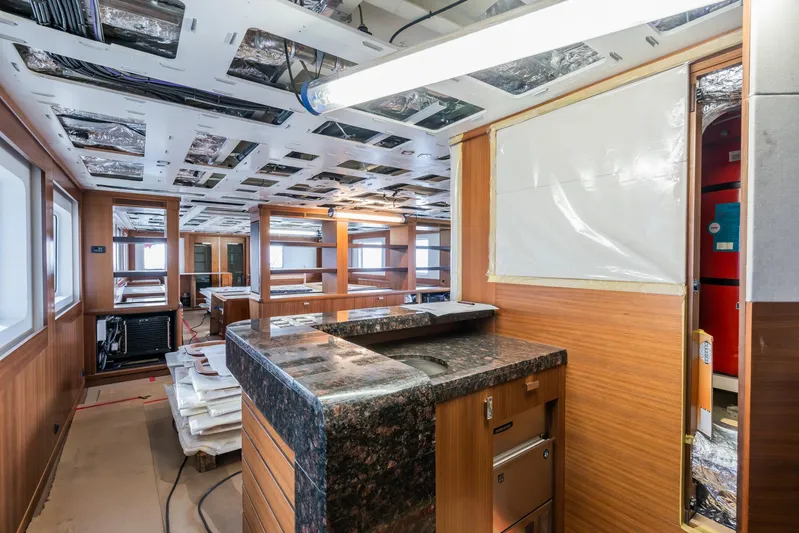 Valeria Yacht Photos Pics Interior of a 1975 Feadship Motoryacht under renovation, featuring wood paneling and granite countertops.