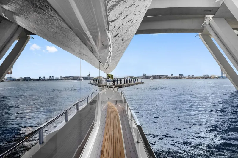Notorious Yacht Photos Pics Sanlorenzo SL106 yacht, 2017 model, cruising under a modern bridge on a sunny day.