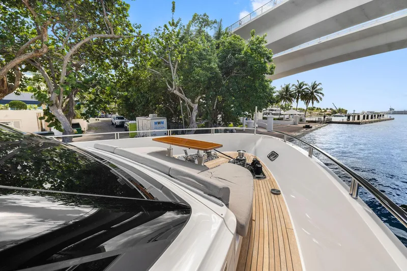 Notorious Yacht Photos Pics Luxurious 2017 Sanlorenzo SL106 yacht docked under a bridge, surrounded by lush greenery.