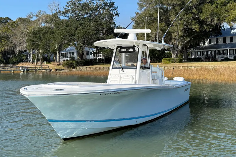  Yacht Photos Pics 2020 Regulator 31 boat on calm water near shoreline with trees and houses.