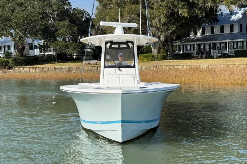  Yacht Photos Pics 2020 Regulator 31 boat on calm water near a shoreline with trees and houses.