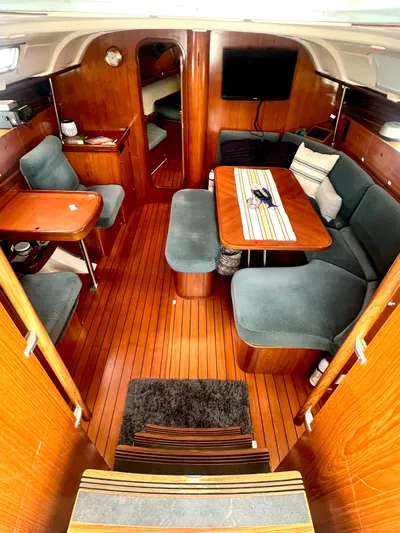 Alpha Carina Yacht Photos Pics Interior of 1993 Beneteau Oceanis 440 sailboat with wooden flooring and cozy seating area.