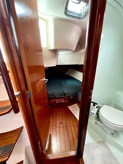 Alpha Carina Yacht Photos Pics Interior cabin of 1993 Beneteau Oceanis 440 sailboat with wooden flooring and compact bathroom.