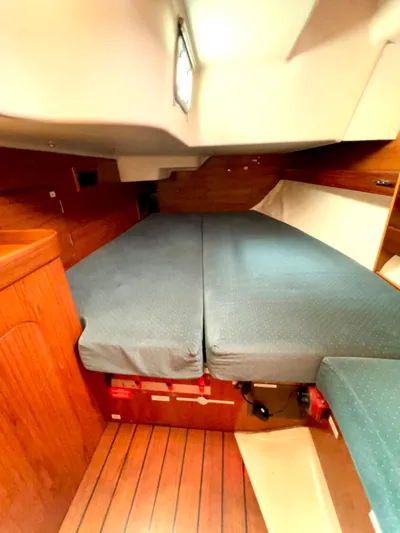 Alpha Carina Yacht Photos Pics Interior cabin of 1993 Beneteau Oceanis 440 sailboat with wooden flooring and cushioned bed.