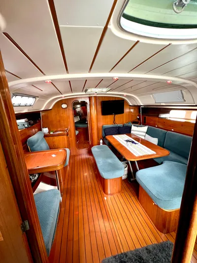 Alpha Carina Yacht Photos Pics Interior of 1993 Beneteau Oceanis 440 sailboat with wood flooring and blue seating.